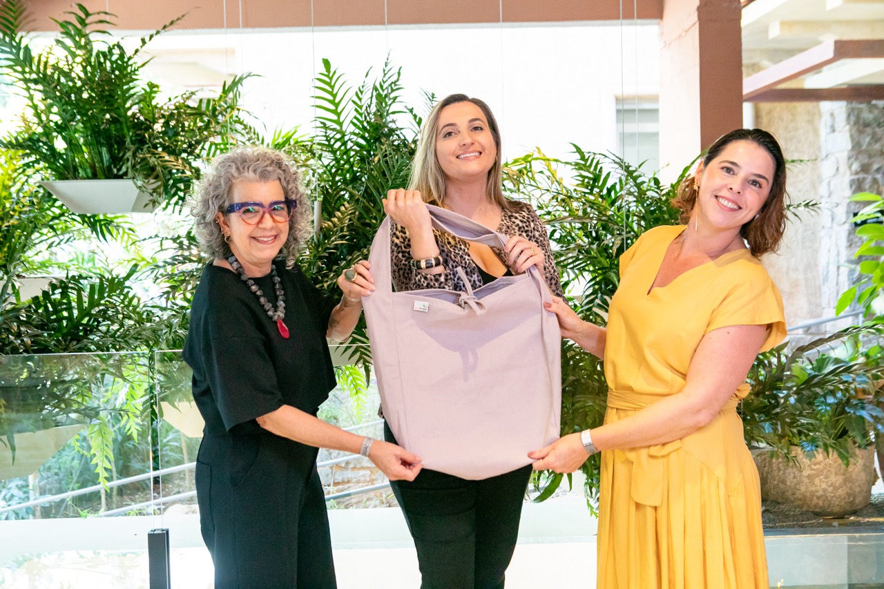 Denise e Gabriela segurando uma bolsa feita de materiais sustentáveis